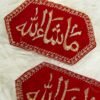 Pair of red hexagonal Mashallah Imam Zamin armbands on white fur background