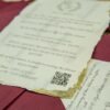 Gold leaf deckle-edge wedding card with monogram wreath close-up