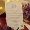 Burgundy wedding invitation envelope with gold wax seal and black satin ribbon