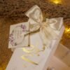 Close-up ivory bow and floral tag on bid boxes