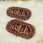 Close-up of gold Mashallah calligraphy on dark maroon velvet capsule Imam Zamin