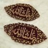 Close-up of gold Mashallah calligraphy on dark maroon velvet Imam Zamin