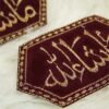 Close-up of gold Mashallah calligraphy on maroon hexagonal Imam Zamin