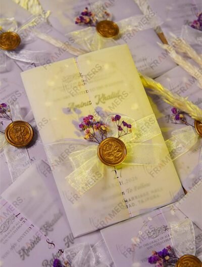 Pastel yellow vellum wedding invitation with gold wax seal and purple dried flowers