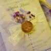 Close-up of yellow organza ribbon bow with wax seal and lavender baby's breath