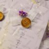 Multiple yellow vellum wedding cards with purple flower accents flat lay