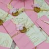 Pink envelope wedding card with gold cord and wax seal on fur backdrop