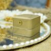 Close-up of premium white velvet ring box with gold trim on a mirror ring tray surface