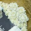 Alternate angle of personalized wedding ring tray showing cascading white roses and LED ring boxes