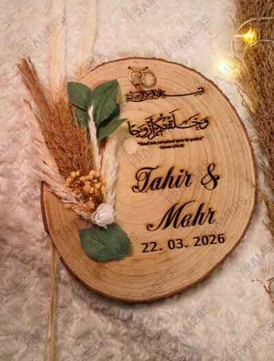 Rustic wood slice nikkah ring tray with laser-engraved Quranic verse, personalized names, pampas grass, and eucalyptus