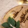 Close-up of laser-engraved Arabic Quranic calligraphy and rings on natural wood slice ring tray