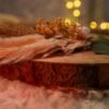 Detail of dried pampas grass, eucalyptus leaves, and white silk rose bouquet on rustic ring tray