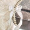 Close-up of pearl and crystal rhinestone border with white bow on minimalist engagement ring tray