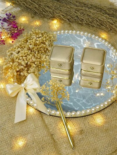 Top view of marble mirror ring tray with gold velvet ring boxes and pearl border