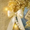 Close-up of dried golden baby's breath and satin bow accent on marble ring tray