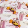 Close-up of hands exchanging rings on engagement favor card