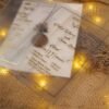 Transparent vellum bi-fold wedding invitation with gold foil on burlap with fairy lights