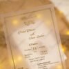 Vellum wedding invitation with gold foil border styled with warm lighting